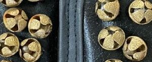 A close up of some gold bells on a black background