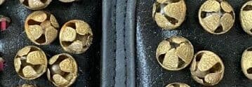 A close up of some gold bells on a black background