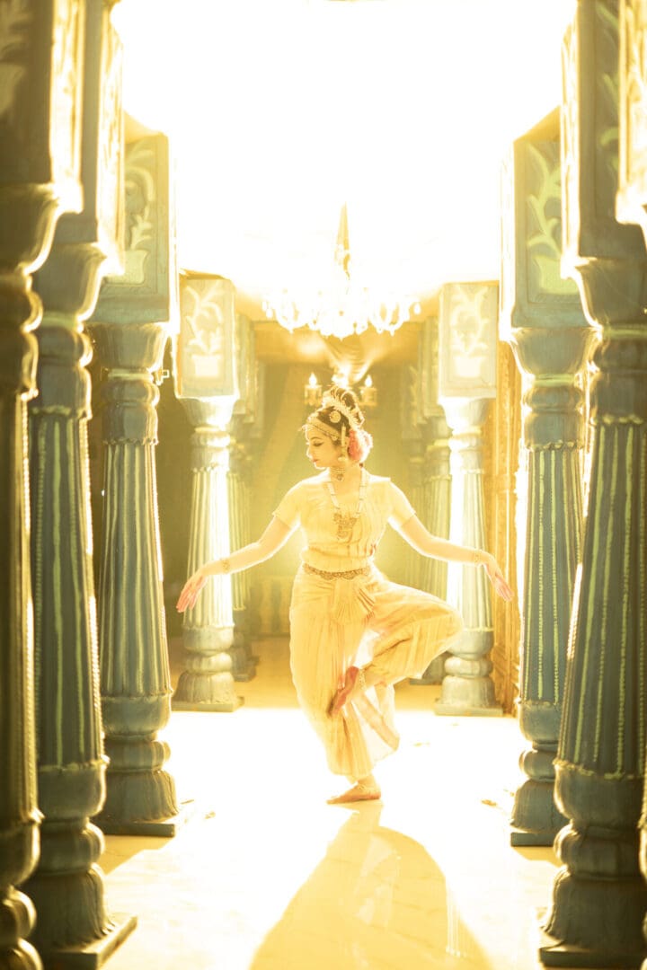 A woman in white dress standing inside of an archway.